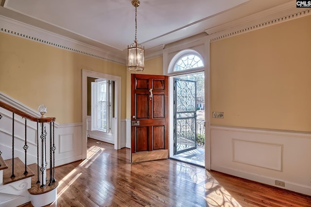 entryway featuring a notable chandelier, wood-type flooring, and ornamental molding