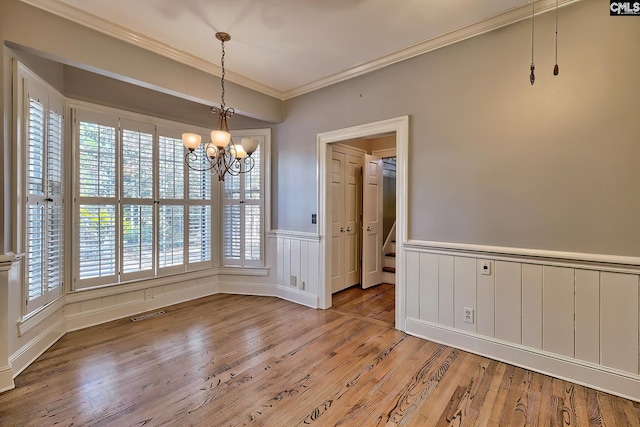 unfurnished dining area with an inviting chandelier, hardwood / wood-style floors, and ornamental molding