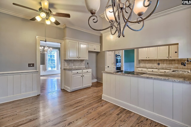 kitchen featuring light stone counters, kitchen peninsula, double oven, and white cabinets