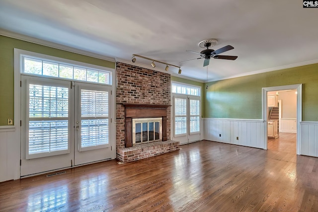 unfurnished living room featuring hardwood / wood-style floors, a fireplace, ornamental molding, and ceiling fan