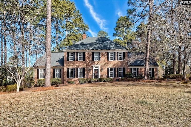 colonial-style house featuring a front lawn