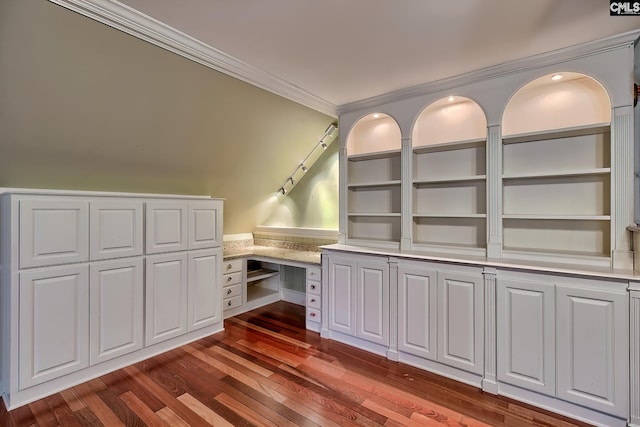 unfurnished office with crown molding, dark wood-type flooring, built in desk, and built in shelves