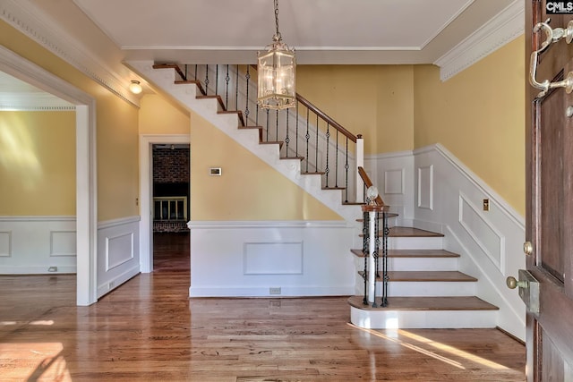 stairs featuring ornamental molding, hardwood / wood-style floors, and an inviting chandelier