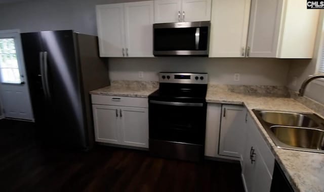 kitchen featuring electric stove, black fridge, dark wood-type flooring, white cabinets, and sink