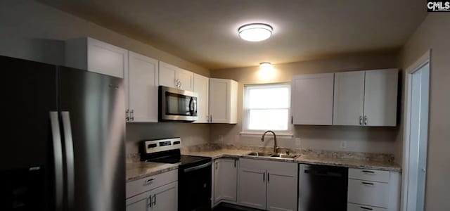 kitchen with light stone counters, sink, white cabinetry, and stainless steel appliances