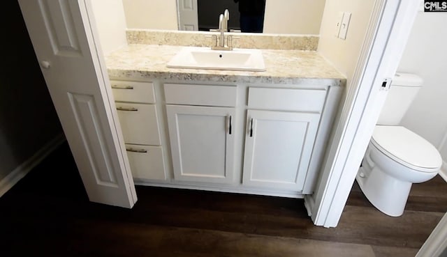 bathroom with toilet, vanity, and wood-type flooring