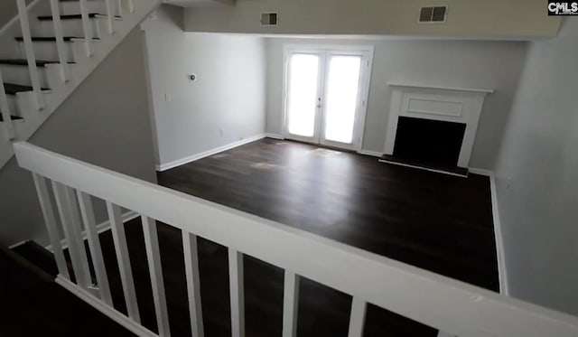 unfurnished living room featuring dark hardwood / wood-style flooring and french doors