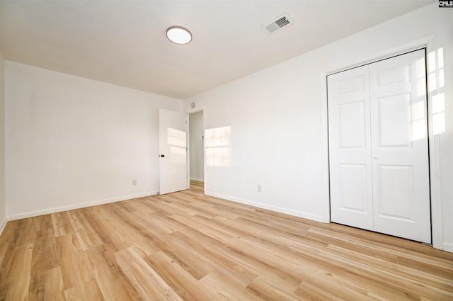 unfurnished bedroom with a closet and light hardwood / wood-style floors