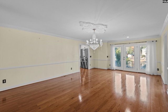 unfurnished living room featuring light wood-type flooring, crown molding, and an inviting chandelier