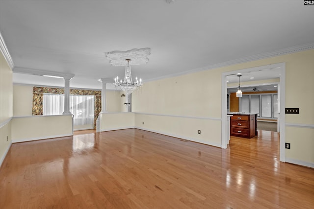 spare room featuring a chandelier, light wood-type flooring, and ornamental molding