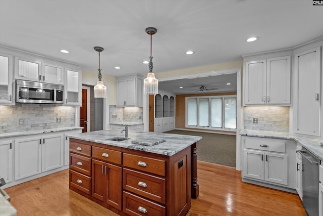 kitchen featuring ceiling fan, appliances with stainless steel finishes, pendant lighting, white cabinets, and a center island