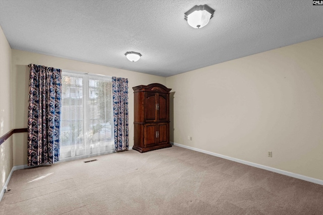 carpeted empty room featuring a textured ceiling