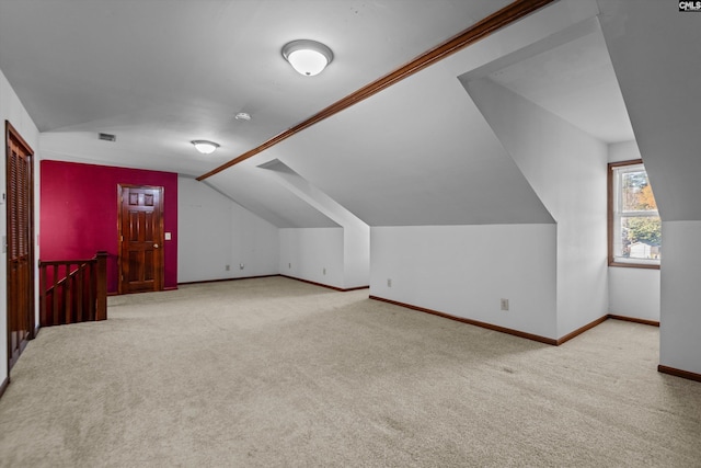 additional living space featuring light carpet and vaulted ceiling