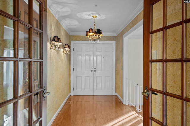 doorway to outside featuring an inviting chandelier, crown molding, and hardwood / wood-style flooring