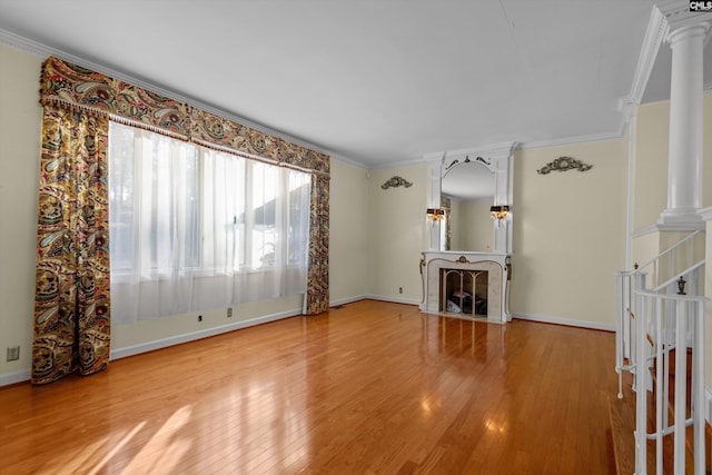 unfurnished living room with decorative columns, hardwood / wood-style floors, and ornamental molding