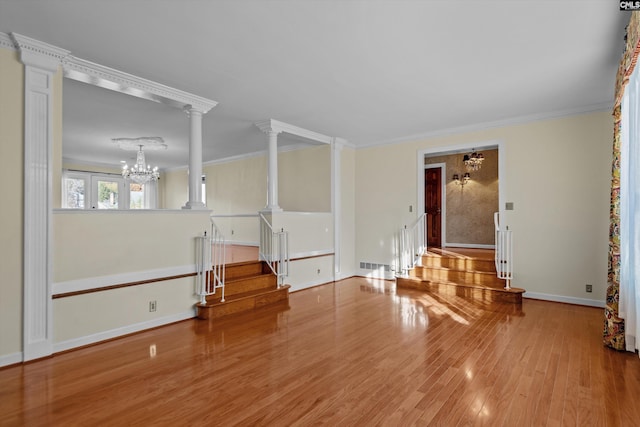 unfurnished living room with decorative columns, crown molding, light hardwood / wood-style floors, and a notable chandelier