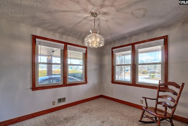 unfurnished room with carpet floors, a textured ceiling, and an inviting chandelier