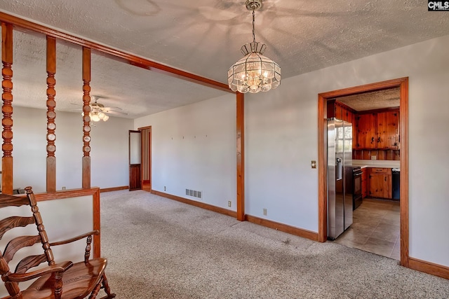 carpeted empty room with ceiling fan with notable chandelier and a textured ceiling