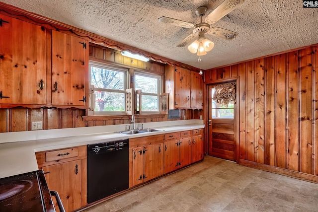 kitchen featuring ceiling fan, dishwasher, wood walls, sink, and a textured ceiling