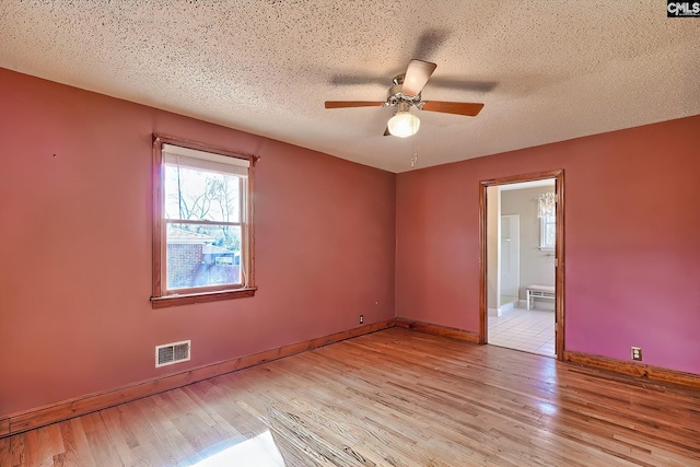 empty room featuring ceiling fan, a textured ceiling, and light hardwood / wood-style flooring