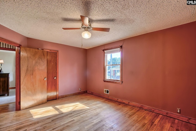 unfurnished bedroom featuring ceiling fan, light wood-type flooring, and a textured ceiling