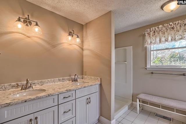 bathroom with a shower, a textured ceiling, tile patterned floors, and vanity