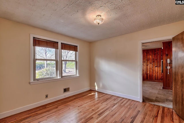 empty room with a textured ceiling and light hardwood / wood-style floors