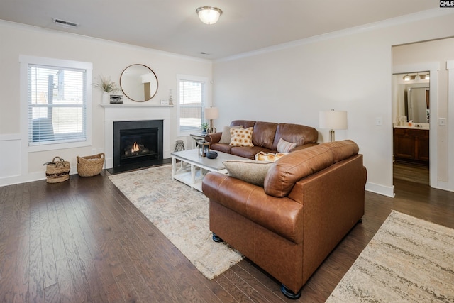 living room with dark wood-type flooring, crown molding, and a healthy amount of sunlight