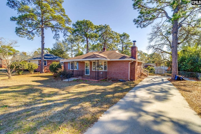 ranch-style home with a front lawn, a storage unit, and covered porch