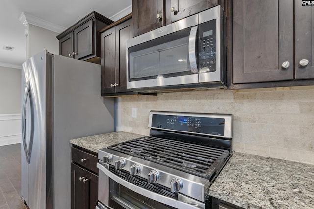 kitchen featuring crown molding, dark wood-type flooring, stainless steel appliances, dark brown cabinets, and light stone counters