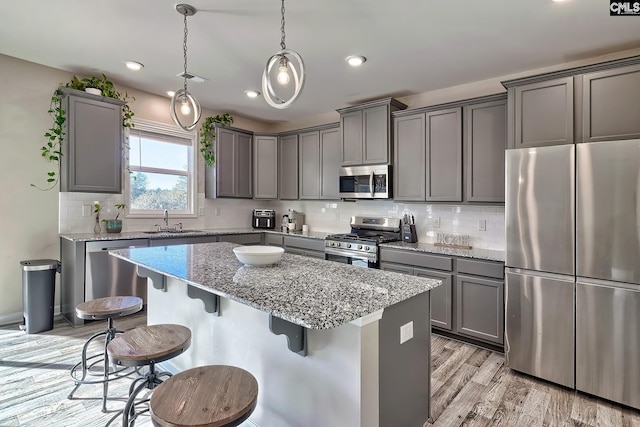 kitchen with appliances with stainless steel finishes, gray cabinetry, hanging light fixtures, and sink