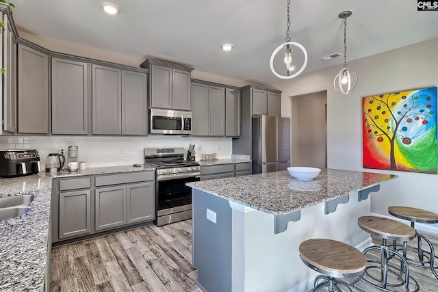 kitchen featuring gray cabinetry, stainless steel appliances, dark stone counters, and tasteful backsplash