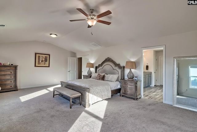 carpeted bedroom with ceiling fan, vaulted ceiling, and ensuite bathroom