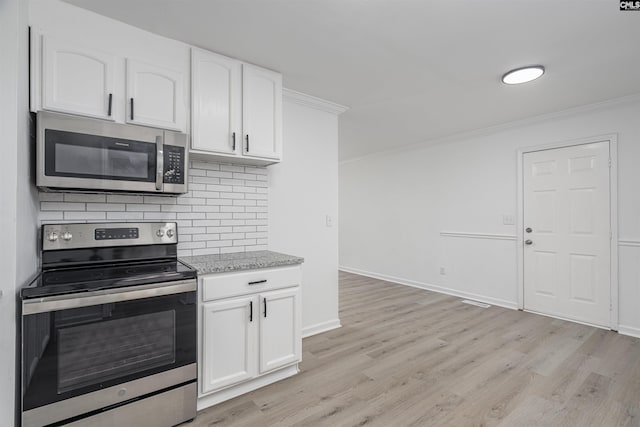 kitchen with light stone countertops, white cabinets, appliances with stainless steel finishes, decorative backsplash, and ornamental molding