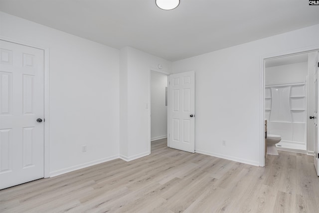 unfurnished bedroom with ensuite bath and light wood-type flooring