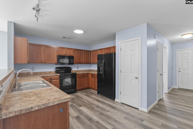 kitchen featuring sink, black appliances, and light wood-type flooring