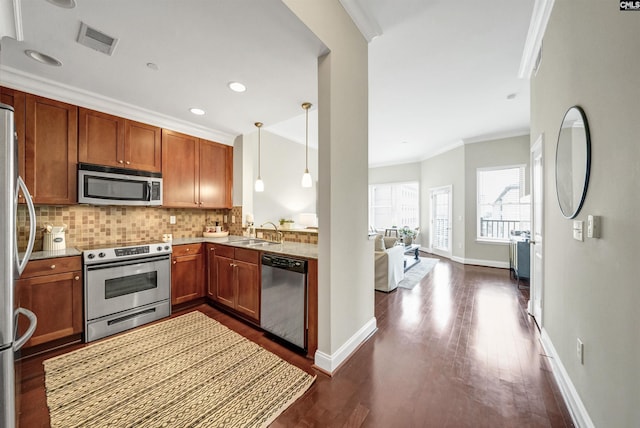 kitchen featuring pendant lighting, appliances with stainless steel finishes, sink, backsplash, and ornamental molding