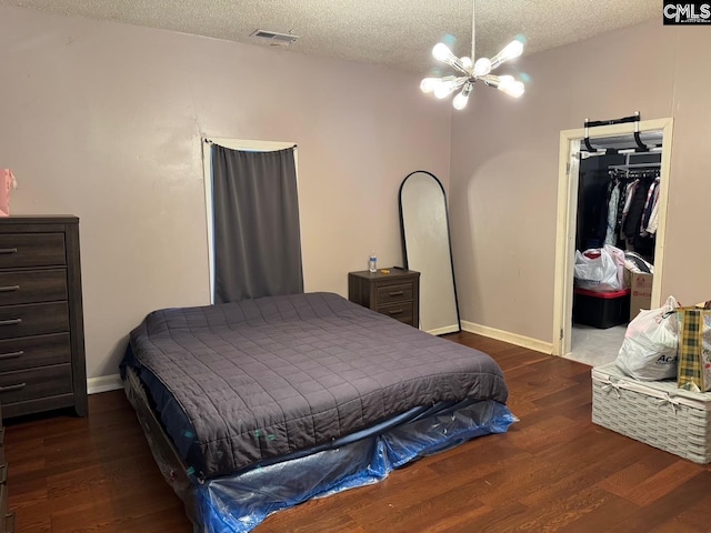 bedroom with a textured ceiling, a closet, dark hardwood / wood-style flooring, and a notable chandelier