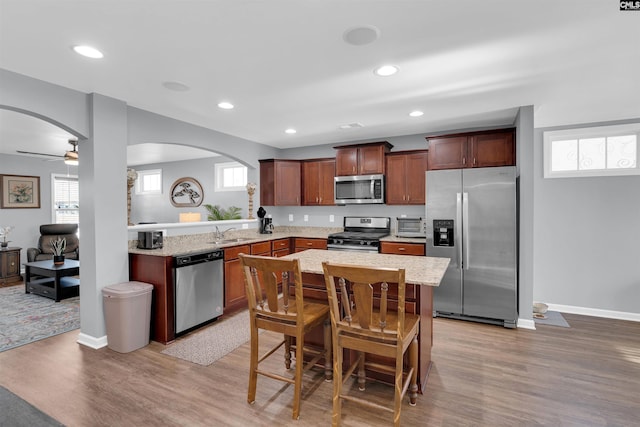 kitchen featuring ceiling fan, light hardwood / wood-style floors, a kitchen bar, sink, and stainless steel appliances