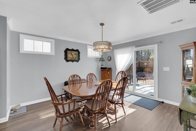 dining space featuring dark wood-type flooring, plenty of natural light, ornamental molding, and a notable chandelier