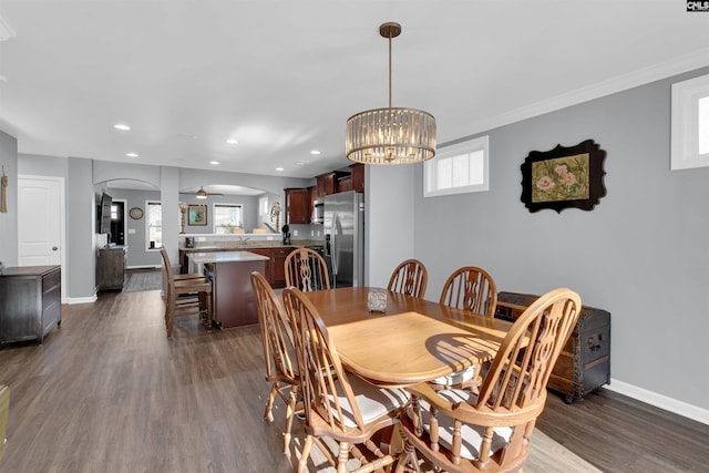 dining area featuring dark wood-type flooring, plenty of natural light, and ceiling fan with notable chandelier