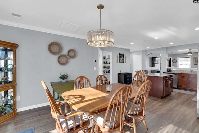 dining room with crown molding, dark hardwood / wood-style floors, sink, and ceiling fan with notable chandelier