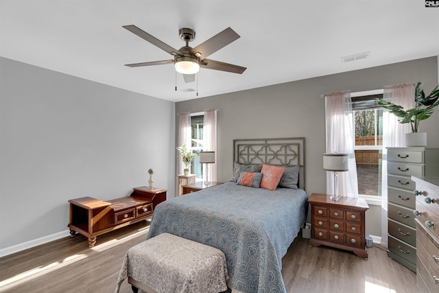 bedroom featuring ceiling fan, wood-type flooring, and multiple windows