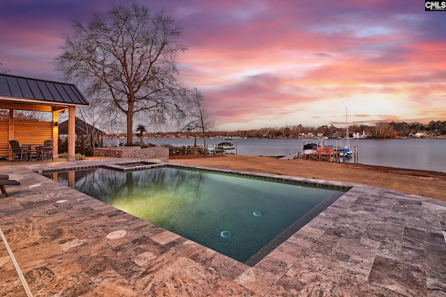 pool at dusk featuring a patio area and a water view