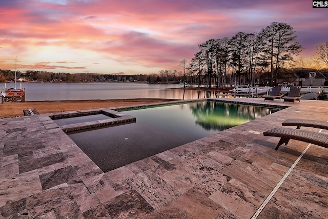 pool at dusk featuring a water view