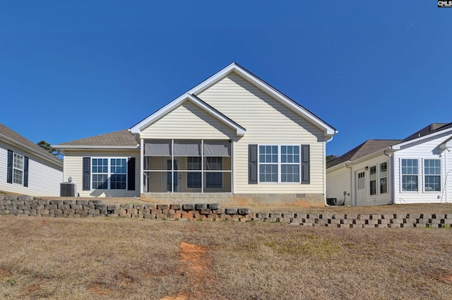 back of property with a lawn, central air condition unit, and a sunroom