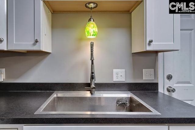 interior details featuring sink, pendant lighting, and white cabinets