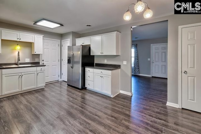 kitchen featuring dark hardwood / wood-style floors, white cabinetry, stainless steel fridge, and sink