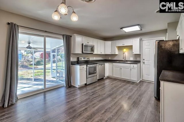 kitchen featuring decorative light fixtures, dark wood-type flooring, white cabinets, and stainless steel appliances