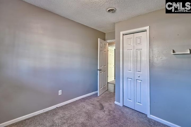 unfurnished bedroom featuring a textured ceiling, a closet, and carpet floors